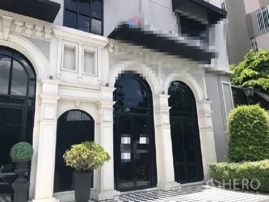 พื้นที่ขายปลีก ให้เช่าในHuai Khwang, Bangkok - ด้านหน้าพื้นที่ร้านค้ากระจกโค้งสูง กรอบสีดำ รายละเอียดหินสีขาว พื้นลายตาราง และต้นไม้จัดสวน