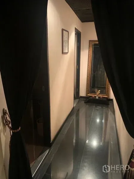 零售空间 出租在Bang Rak, Bangkok - 狭长过道，黑色地砖、米色墙面、厚帘与大镜子。