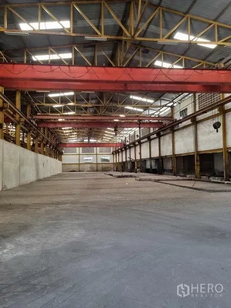 Warehouse for rent in Phra Pradaeng, Samut Prakan - Open production hall featuring multiple red overhead cranes, concrete floor and long-span roof trusses.