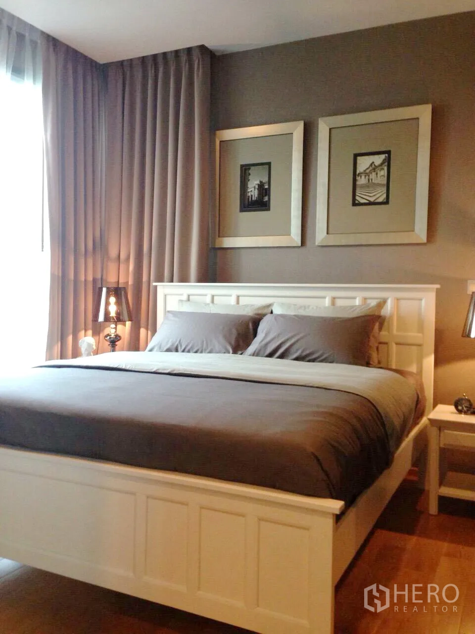 公寓 出租在Khlong Toei, Bangkok - 温馨主卧，白色床架、灰色床品、木地板与装饰画。