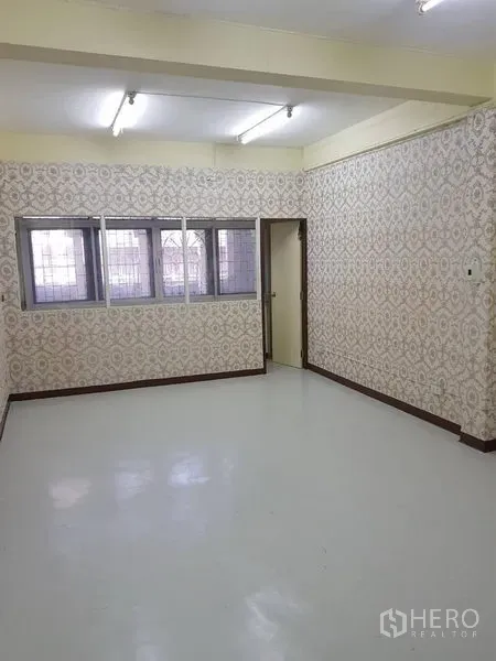 พื้นที่ขายปลีก ให้เช่าในKhlong Toei, Bangkok - ห้องพื้นที่ค้าปลีกโล่งสว่าง ผนังลวดลาย หน้าต่างมีเหล็กดัด และไฟนีออนบนเพดานเหนือพื้นเงา