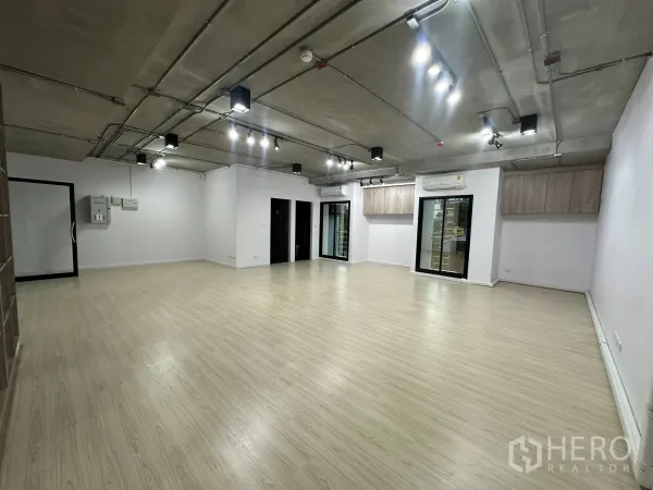 Office Space for rent in Watthana, Bangkok - Empty office area with industrial ceiling, multiple spotlights and glass partitions.