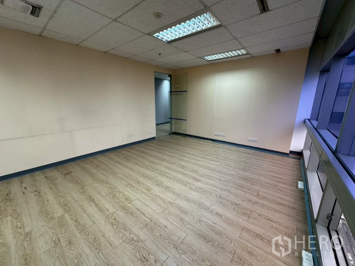 Office Space for rent in Watthana, Bangkok - Bright office room with wood floors and large windows facing nearby towers.