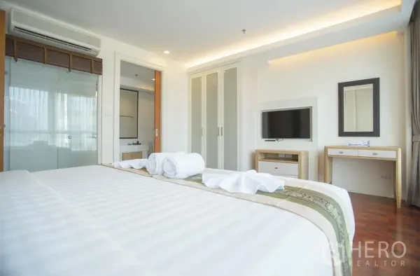 Apartment for rent in Khlong Toei, Bangkok - Master bedroom with king bed, built-in wardrobe, TV console and ensuite bathroom.