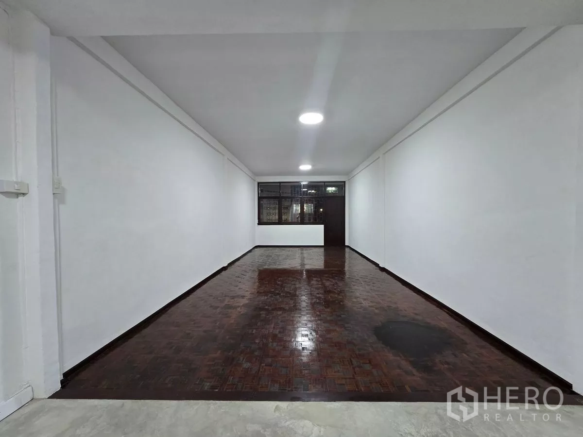 店屋 出租在Watthana, Bangkok - 夜间长形零售大厅，木地板与后方柜台