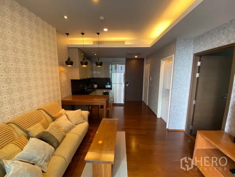 公寓 出租或出售在Watthana, Bangkok - 温馨客厅，配沙发、就餐吧台与高光橱柜，氛围灯柔和。