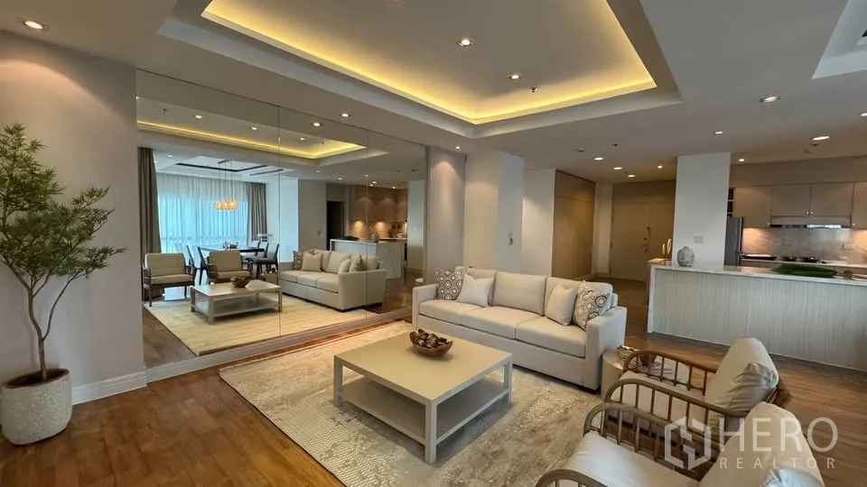 คอนโด for rent in Pathum Wan, Bangkok - ห้องนั่งเล่นแบบเปิดโล่งเชื่อมพื้นที่ทานอาหาร มีโซฟา โต๊ะกลาง ผนังกระจกเงาบานใหญ่ ไฟดาวน์ไลท์ และครัวพร้อมเคาน์เตอร์