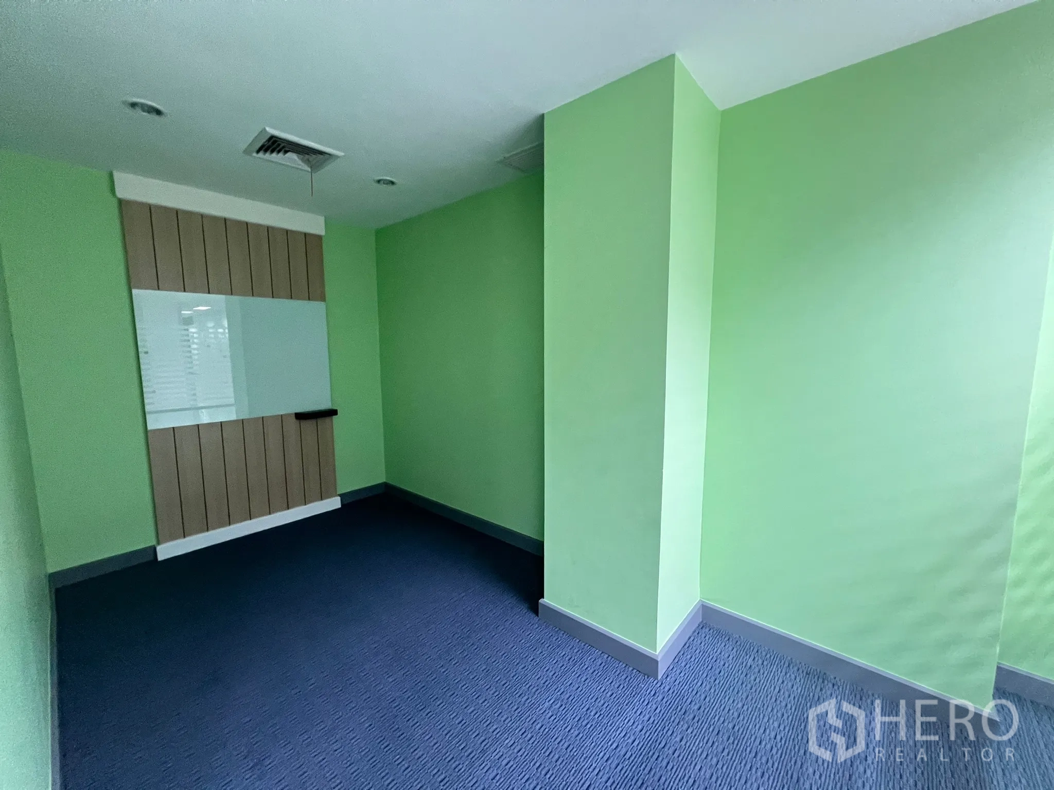 零售空间 出租 - 小型房间，绿色墙面、地毯地面，并设有白板。