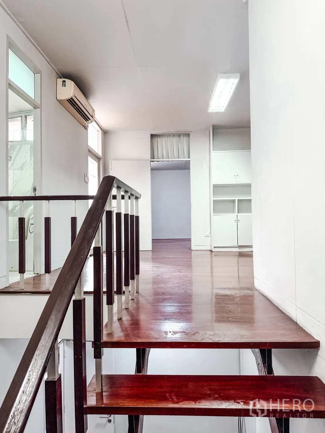 家庭办公室 for rent in Watthana, Bangkok - 深色木质楼梯与扶手通往楼上平台，内置柜与空调可见。