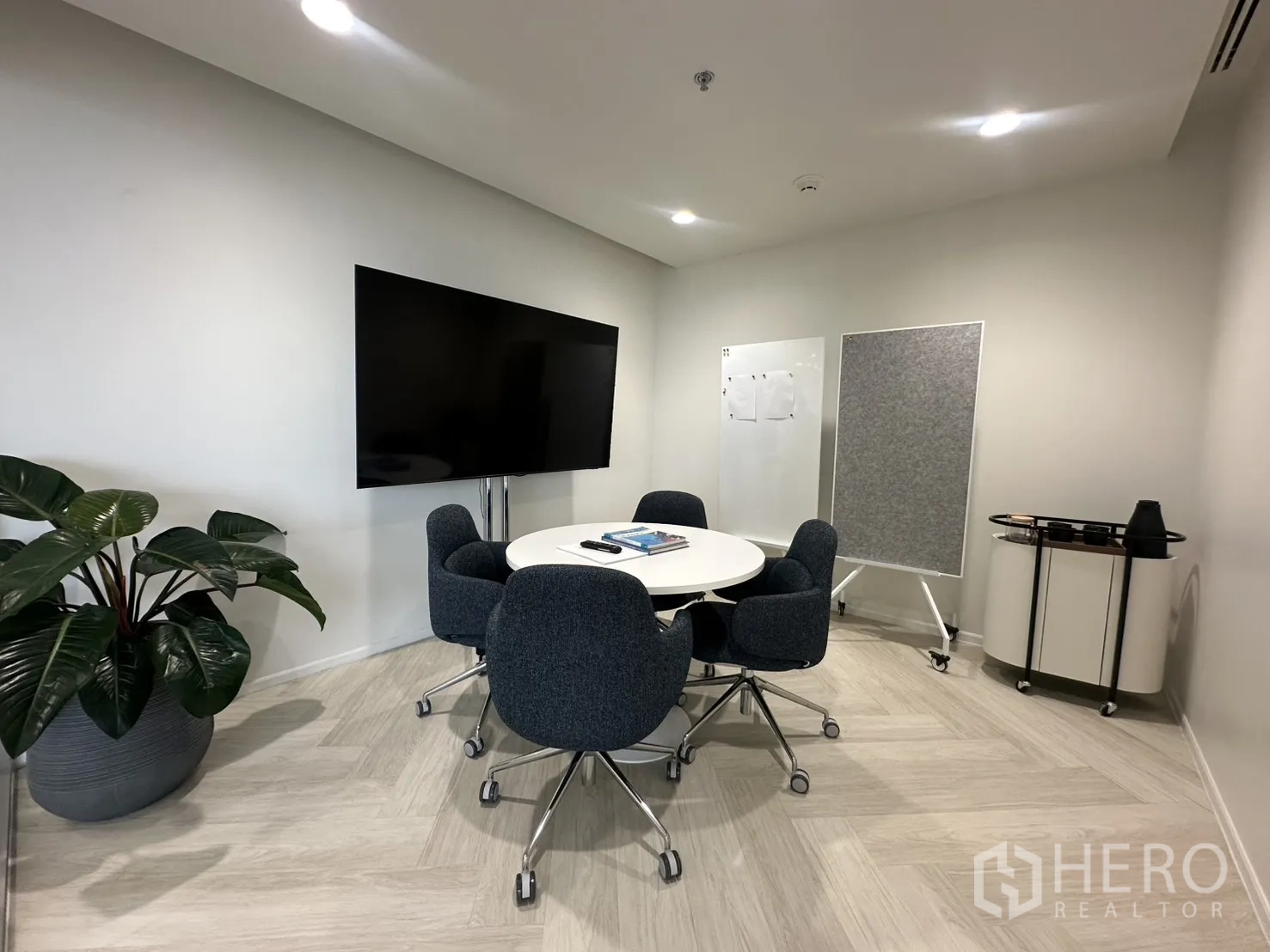 Office Space for rent in Sathon, Bangkok - Enclosed meeting room with round table, big TV screen, whiteboard, rolling cart, and a large plant.