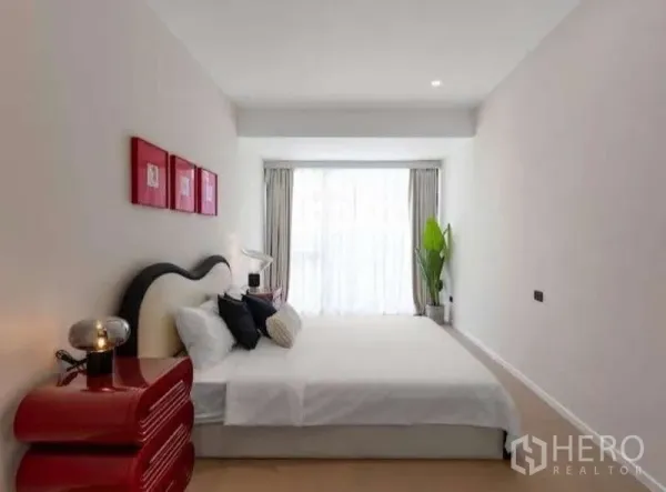 Townhouse for sale in Sathon, Bangkok - Bright primary bedroom with large window, white bedding and red bedside tables.