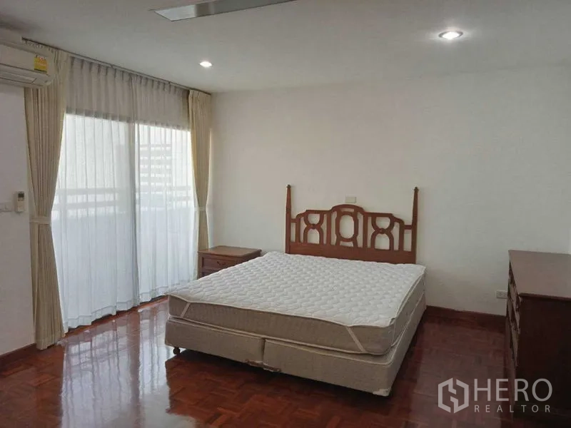 Condominium for rent in Watthana, Bangkok - Bright bedroom with double bed, bedside tables and floor-to-ceiling windows with curtains.