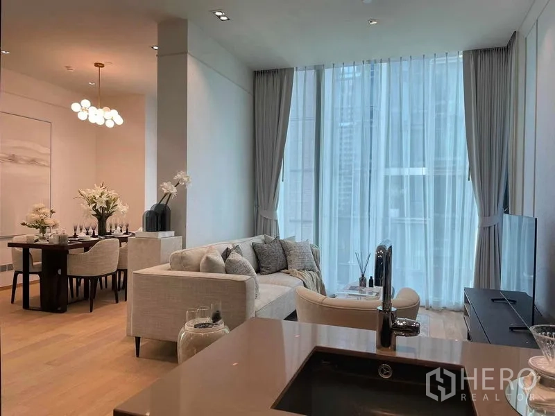 Condominium for rent in Pathum Wan, Bangkok - Open-plan living and dining area with floor-to-ceiling windows and light wood floors in a modern Bangkok condo.