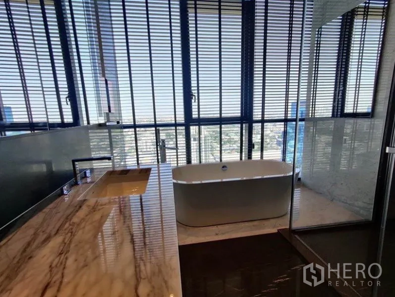 Condominium for rent in Watthana, Bangkok - Luxury bathroom with freestanding bathtub by the window, marble vanity, and glass-enclosed shower.