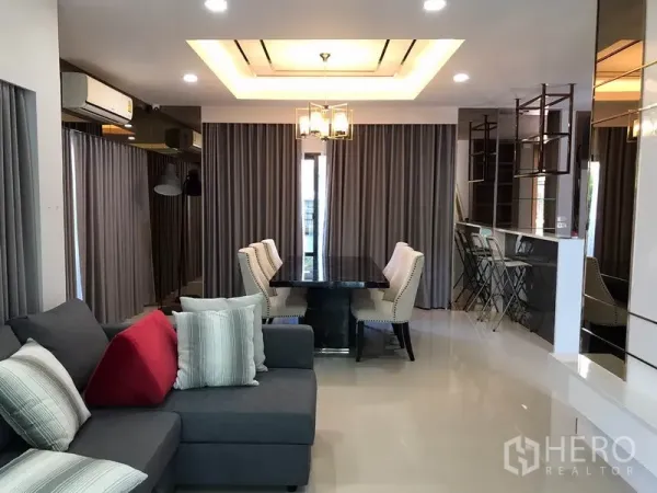 Detached House for rent in Bang Phli, Samut Prakan - Open-plan lounge and dining area with tray ceiling, chandelier and six-seat dining table.