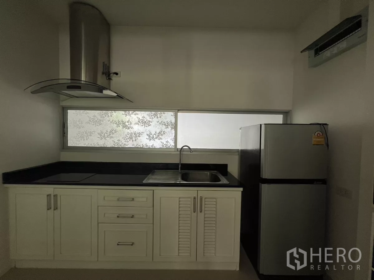 Townhouse for rent in Suan Luang, Bangkok - Kitchen featuring a refrigerator, sink, and frosted window for light and privacy.