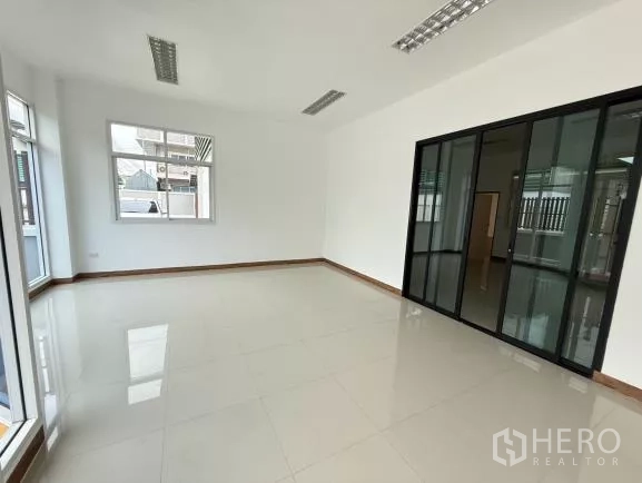 โรงงาน ขายในThanyaburi, Pathum Thani - ห้องสำนักงานชั้นล่างสว่าง โทนขาว พื้นกระเบื้อง ไฟฟลูออเรสเซนต์ และผนังกระจกกรอบอลูมิเนียมสีดำ
