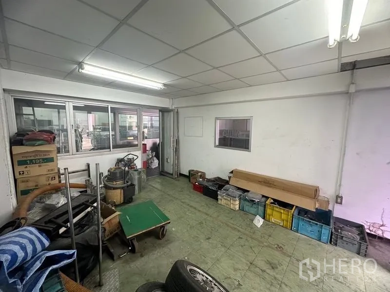 Factory for rent or sale in Khlong Luang, Pathum Thani - Utility room beside the workshop with fluorescent lights and storage bins.