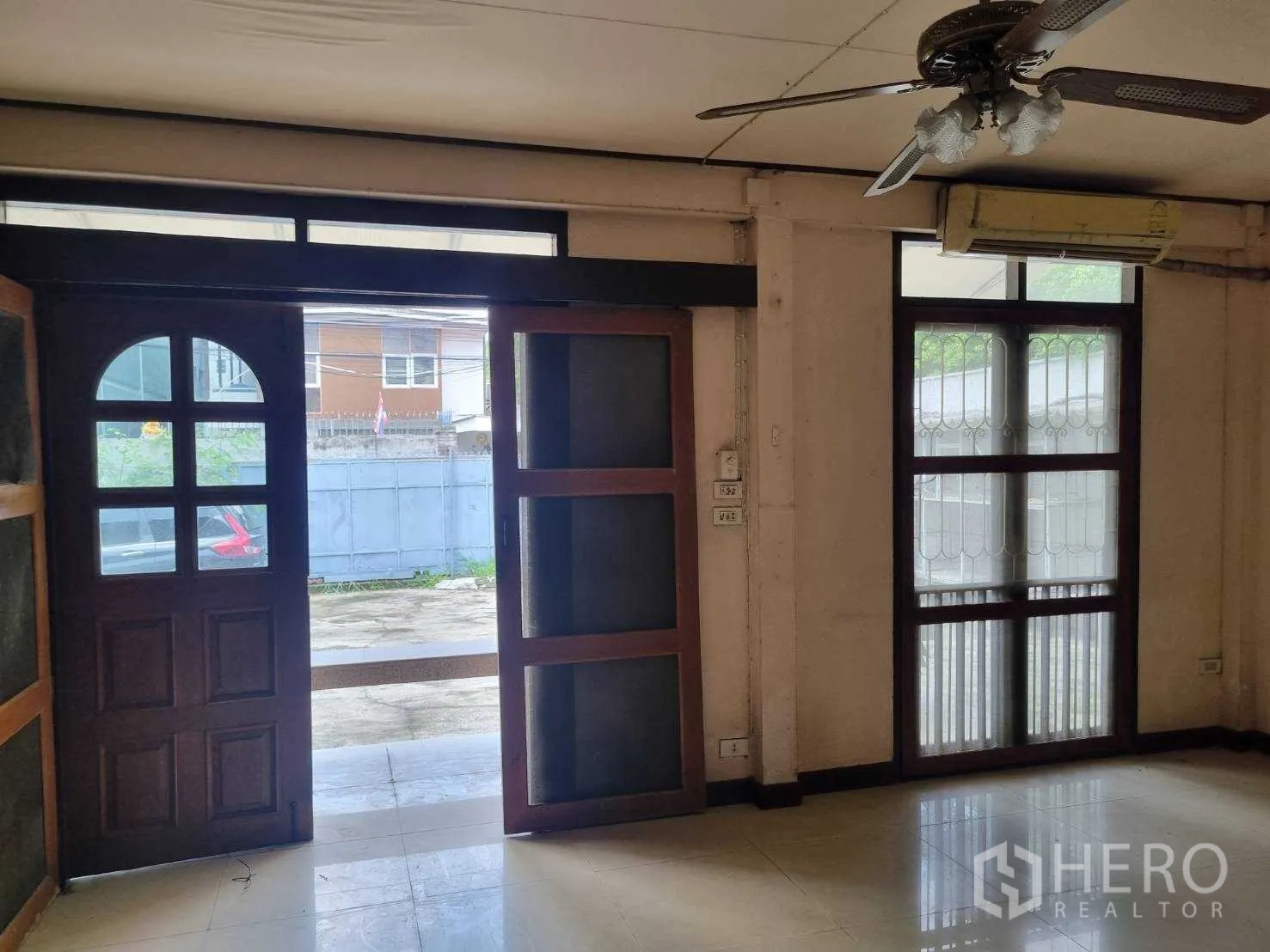 Detached House for rent or sale in Watthana, Bangkok - Entry area with arched wooden door, sliding windows, ceiling fan and tiled floor.