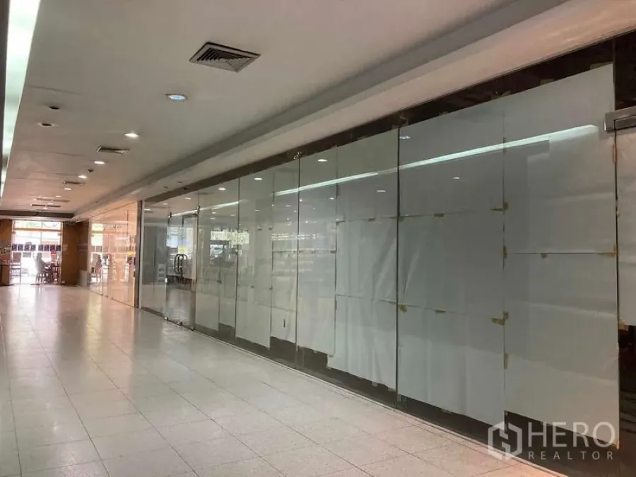 พื้นที่ขายปลีก ให้เช่า - ยูนิตค้าปลีกผนังกระจกหันสู่ทางเดินสว่าง พร้อมไฟเพดานและพื้นกระเบื้องเงา