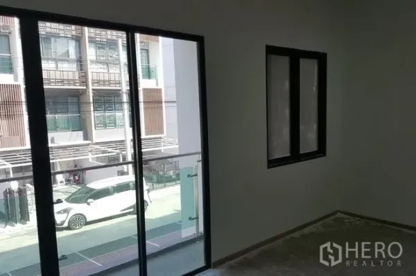 Townhouse for rent in Bueng Kum, Bangkok - Bright room with sliding glass door to a balcony overlooking modern townhomes in Bueng Kum.