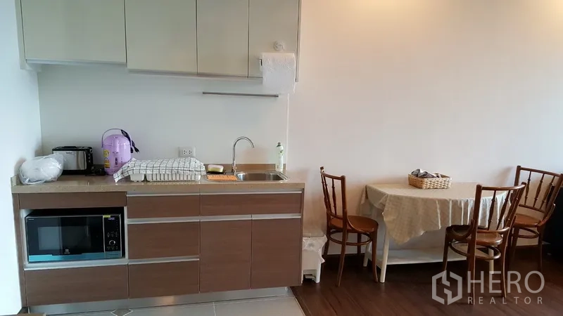 Condominium for rent in Sathon, Bangkok - Compact kitchen with cabinets, sink, microwave and a dining table for four.