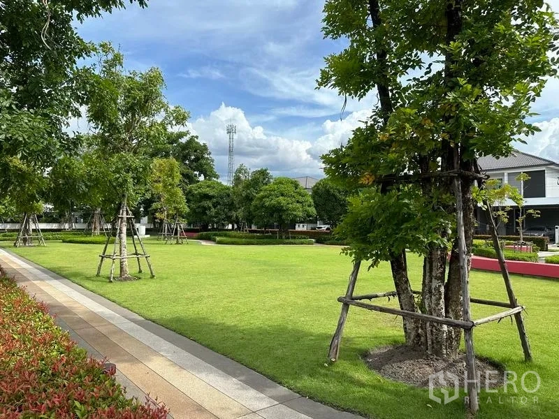 Detached House for sale in Nonthaburi - Lush communal park with open lawn, mature trees and a paved walkway.