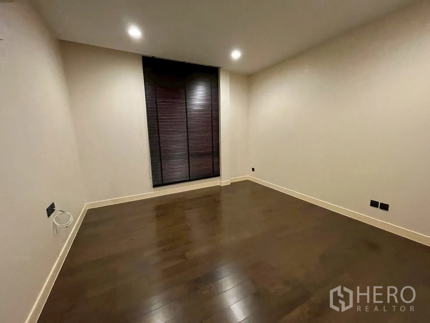 Detached House for rent in Bang Kapi, Bangkok - Empty room with dark wood flooring and a tall window with blinds.