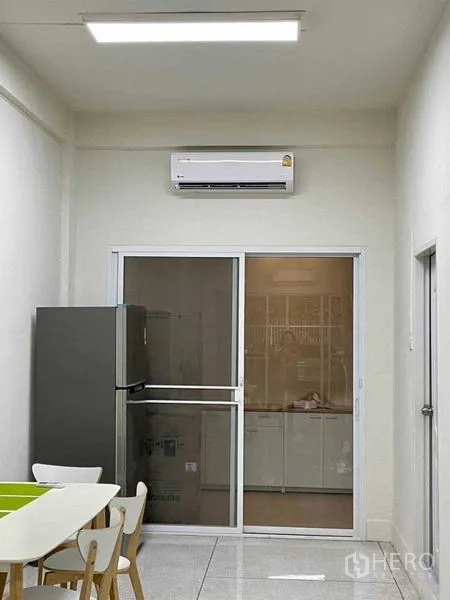 Home Office for rent or sale in Watthana, Bangkok - Compact dining and pantry area with refrigerator, sliding glass door and wall-mounted air conditioner.