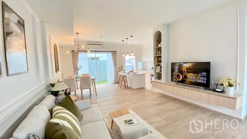 联排别墅 出租在Prawet, Bangkok - 采光充足的客餐厅与开放式厨房，木地板与电视墙