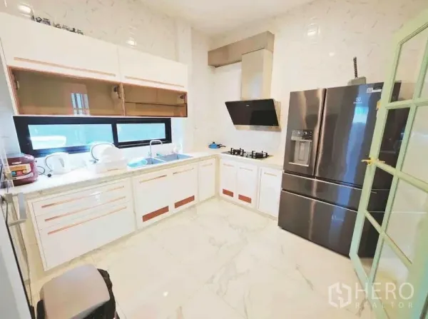 Detached House for rent - Modern L-shaped kitchen with window, gas hob, hood and stainless refrigerator.