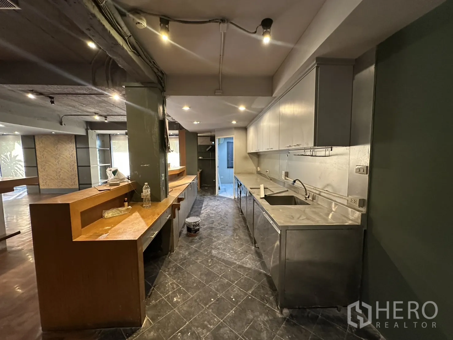 Retail Space for rent in Watthana, Bangkok - Long wooden counter facing a stainless pantry with upper cabinets under warm downlights.