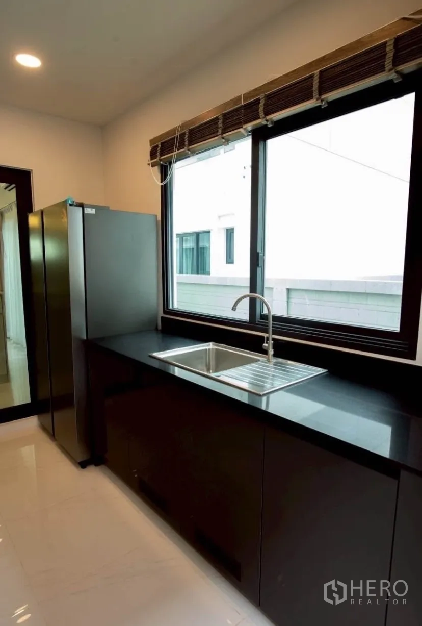 Detached House for rent in Bang Phli, Samut Prakan - Secondary kitchen with black countertop, stainless sink and a large window.