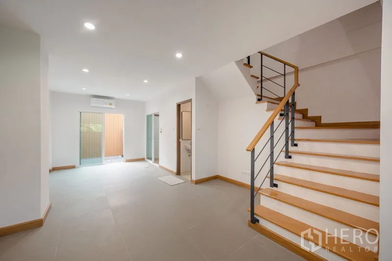 ทาวน์เฮาส์ ขายในLat Phrao, Bangkok - ชั้นล่างโปร่งโล่ง มีบันได ประตูกระจกเลื่อนไปลานหลัง และไฟดาวน์ไลท์