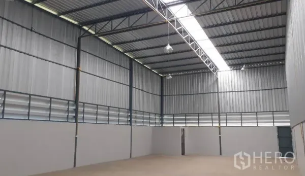 Warehouse for rent in Mueang Pathum Thani, Pathum Thani - High-ceiling metal warehouse interior in Mueang Pathum Thani with skylight strip, ventilation louvers and smooth concrete floor.