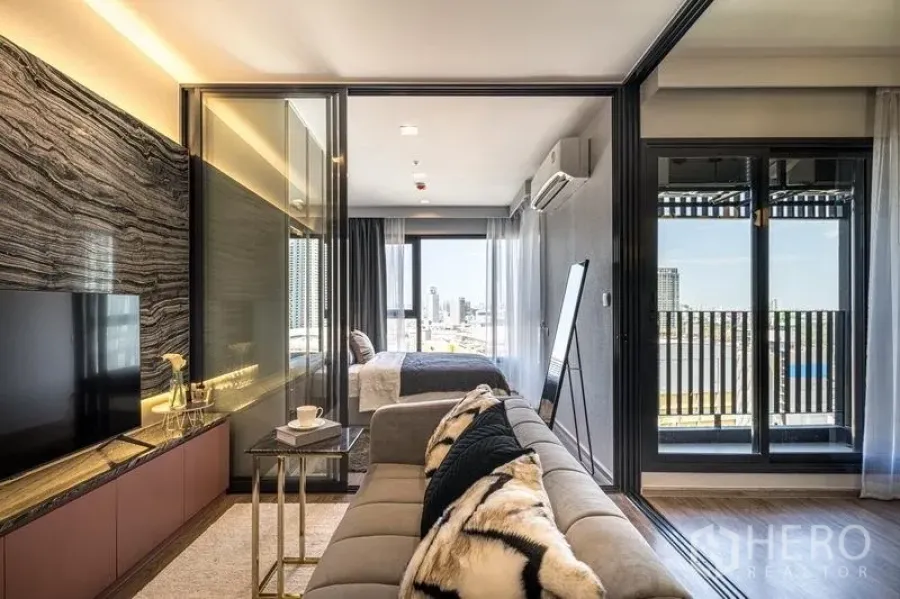 Condominium for sale in Chatuchak, Bangkok - Open-plan living room facing the balcony, glass wall to the bedroom, and a large TV console.