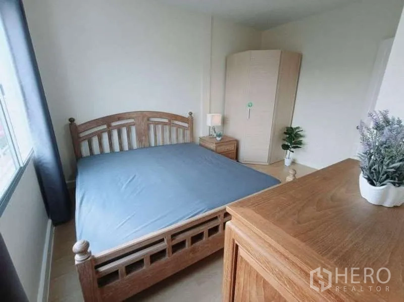 联排别墅 出租在Bang Kapi, Bangkok - 采光充足的卧室，木质床、斗柜、转角衣柜与窗帘。