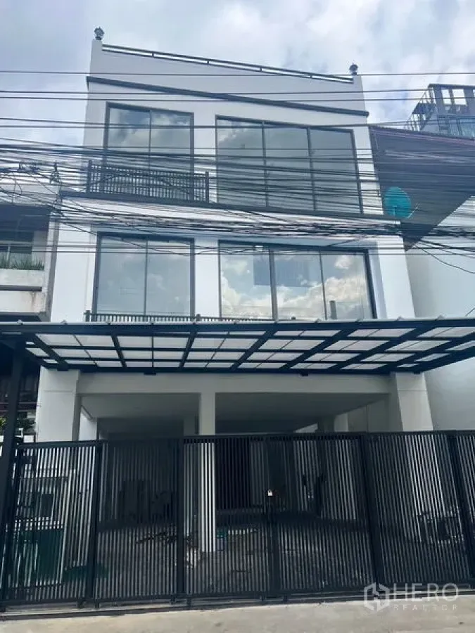带办公室的家 出租或出售在Watthana, Bangkok - 街景视角：黑色金属围栏与玻璃立面的家办楼。