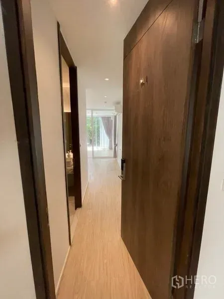 Home Office for rent in Khlong Toei, Bangkok - Entrance hallway with wooden door and recessed lights leading toward a bright glass-partitioned room.