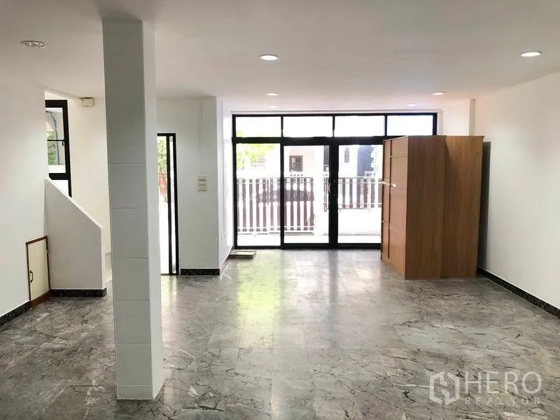 ทาวน์เฮาส์ ให้เช่าในWatthana, Bangkok - ห้องนั่งเล่นแบบโอเพ่นสเปซ พื้นลายหินอ่อน ไฟดาวน์ไลท์ และประตูกระจกบานใหญ่เปิดสู่หน้าบ้าน