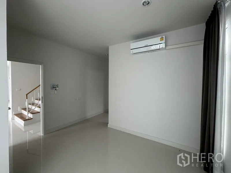 บ้าน ขายในLam Luk Ka, Pathum Thani - ห้องอเนกประสงค์ขนาดกะทัดรัด มีแอร์ ผนังสีขาว และผ้าม่านทึบ