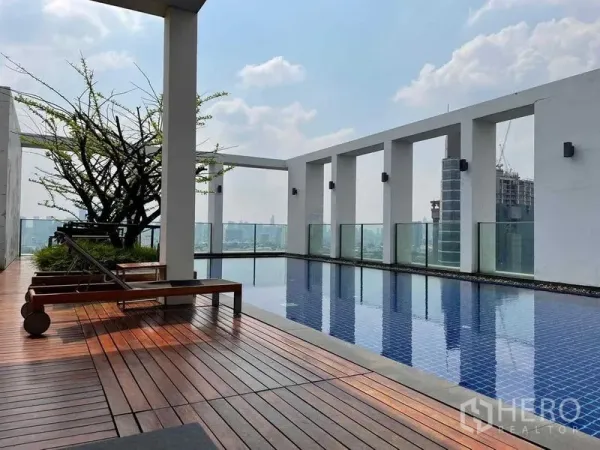 公寓 出售在Phaya Thai, Bangkok - 屋顶泳池配木质平台与躺椅，享城市天际线景观，靠近BTS阿里站