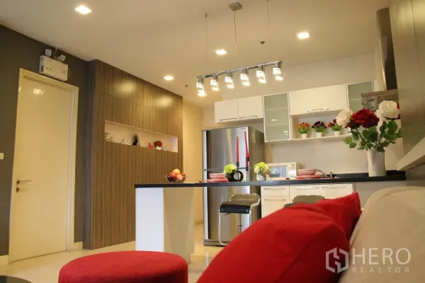 คอนโด ให้เช่าในKhlong Toei, Bangkok - ครัวบิวท์อินสีขาว ตู้เย็นสแตนเลส ชั้นวางของ และที่นั่งบาร์ ใต้ไฟแขวนแบบเส้น