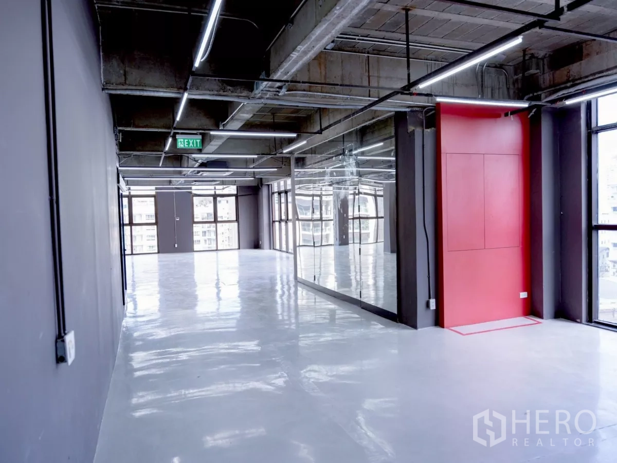 Office Space for rent - Long gallery-like space with mirrored wall, red feature and overhead lighting.