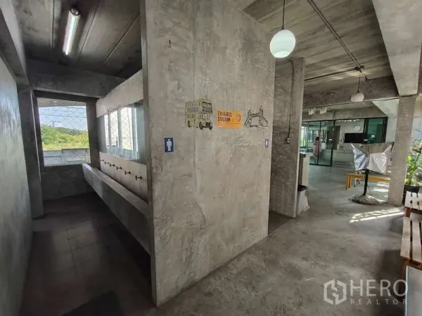 Warehouse for rent in Huai Khwang, Bangkok - Industrial hallway with a long washbasin, signage and polished concrete surfaces.
