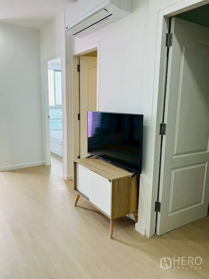 公寓 出租在Bang Rak, Bangkok - 从起居区通往卧室的走廊，电视柜与可见朝向城市的房间。