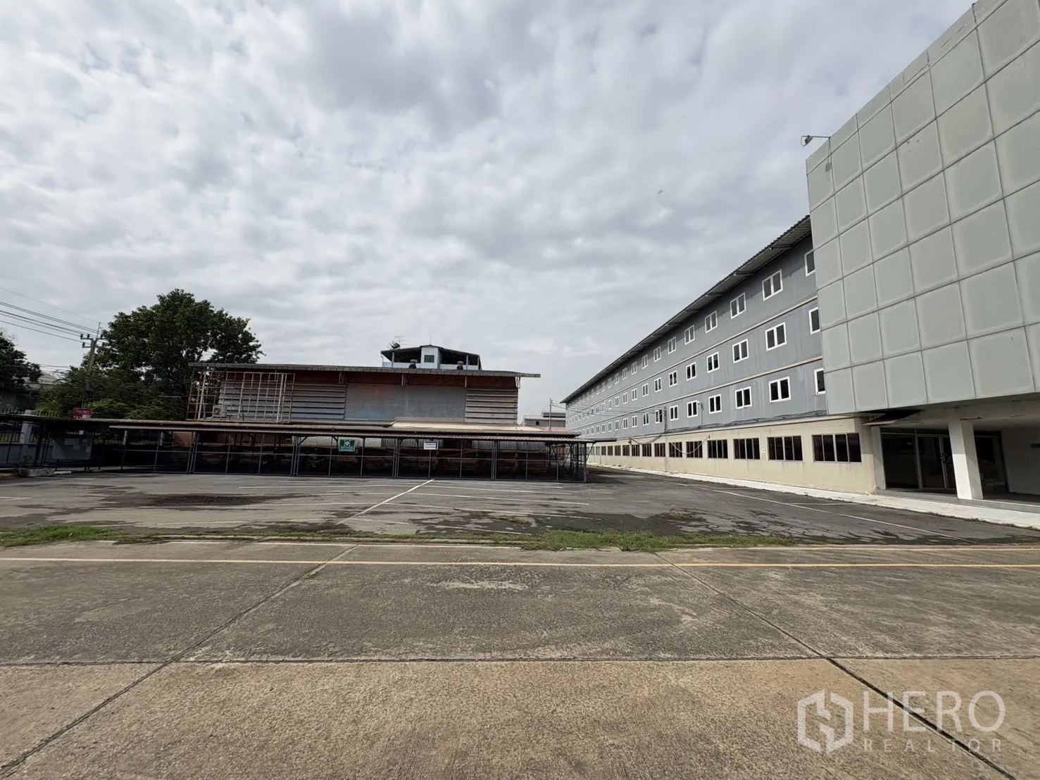 工厂 出租在Phra Pradaeng, Samut Prakan - 宽阔硬化场地与停车区，毗邻多层办公楼。