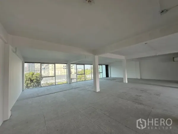 Office Space for rent in Khlong Toei, Bangkok - Corner office area with panoramic glass walls overlooking buildings and trees, open ceiling services.