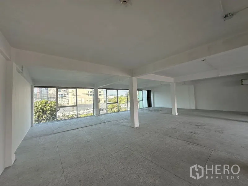 Office Space for rent in Khlong Toei, Bangkok - Corner office area with panoramic glass walls overlooking buildings and trees, open ceiling services.