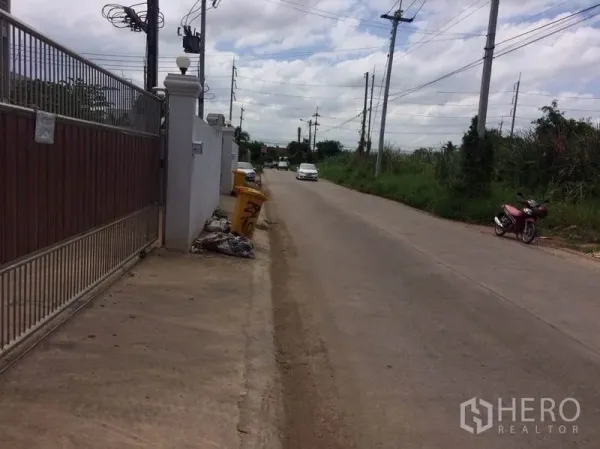 Factory for rent or sale in Mueang Samut Sakhon, Samut Sakhon - Quiet access road beside the property gate with power lines and light traffic.